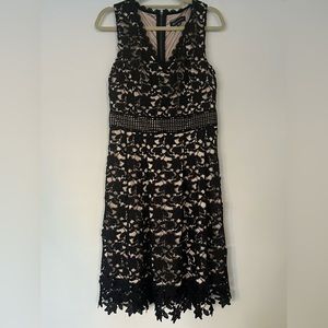 Black lace cocktail dress with decorative neckline and hem - Size M